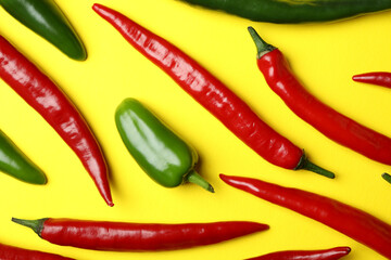 Red and green hot peppers on yellow background