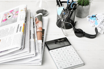 Newspapers with calculator and organizer on table, closeup