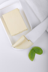 Butter and basil leaves on a white table. Light background.