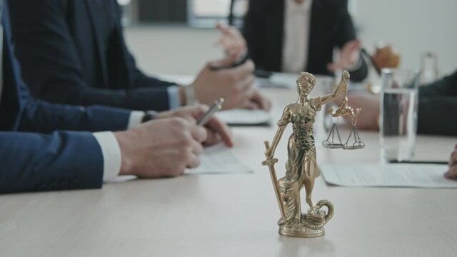 PAN close-up of gold statue of Femida &ndash; Goddess of Justice &ndash; with scales at lawyers conference table during their meeting