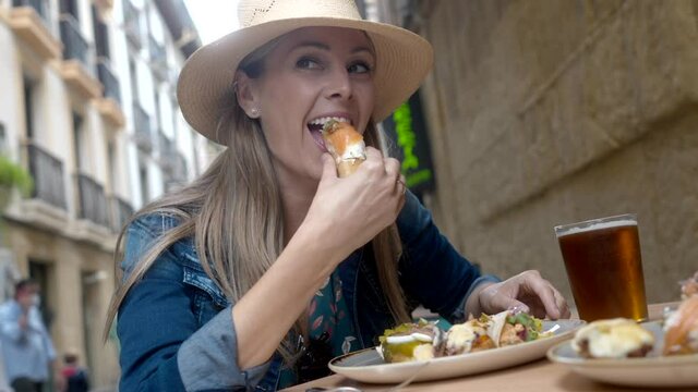 young woman eating tapas in San Sebastian in Spain