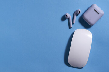 wireless ear piece and mouse on blue background