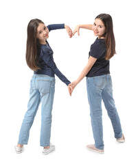 Cute twin girls making heart shape with their hands on white background