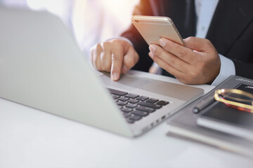 Man hands in black suit sitting and using computer for online payment or shopping online. Business man using mobile phone while working. E-Banking concept
