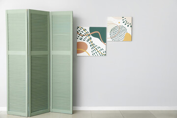 Modern folding screen and pictures hanging on light wall