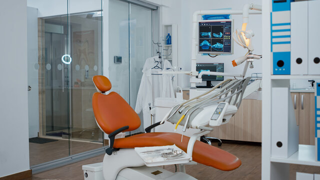 Revealing shot of orthodontic chair with nobody in, teeth x ray images on modern display. Empty medical clinic stomatology hospital room with dentistry equipment, ready for dental heath treatment