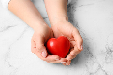 Female hands with red heart on light background, closeup