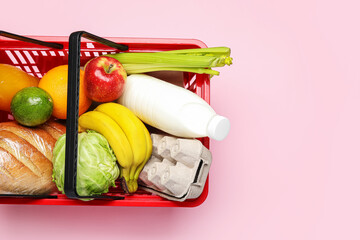 Shopping basket with food on color background