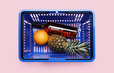 Shopping basket with bottle of wine and fruits on color background