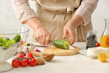 Woman preparing tasty Greek salad in kitchen