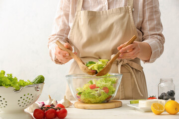 Woman preparing tasty Greek salad in kitchen