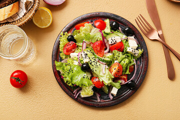 Plate with tasty Greek salad and glass of water on color background