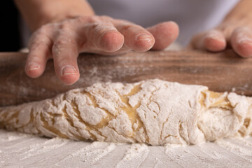 Woman baker rolls out dough at the bakery.