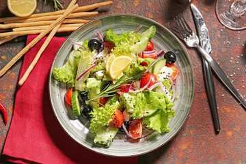 Plate with tasty Greek salad and grissini on grunge background