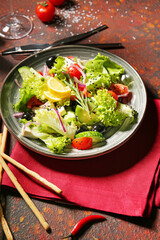 Plate with tasty Greek salad and grissini on grunge background