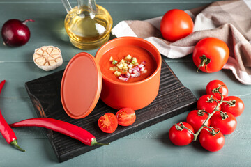 Bowl with tasty gazpacho and vegetables on color wooden background