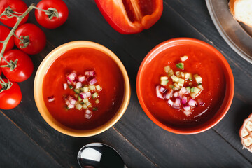 Bowls with tasty gazpacho on dark wooden background, closeup