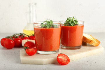 Glasses with tasty gazpacho on light background