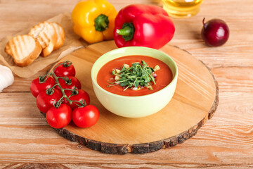 Bowl with tasty gazpacho and vegetables on wooden background
