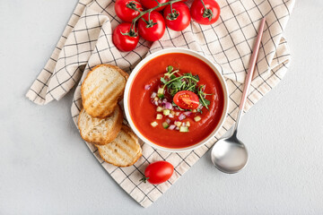 Bowl with tasty gazpacho and bread slices on light background