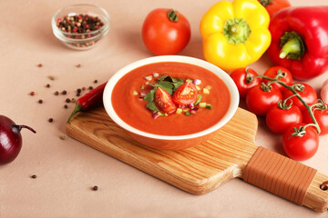 Bowl with tasty gazpacho and vegetables on color background