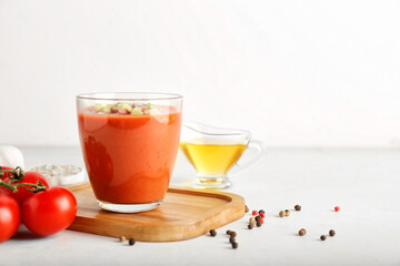 Glass with tasty gazpacho on light background