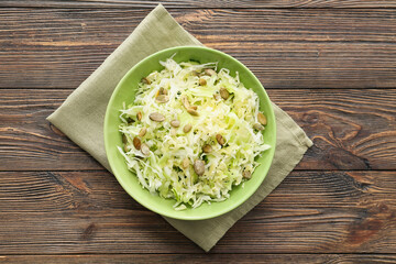 Bowl with tasty cabbage salad on wooden table