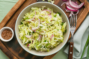 Bowl with tasty cabbage salad on color wooden background