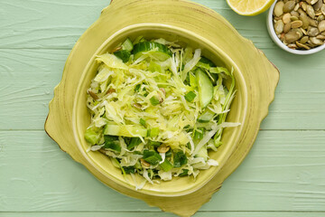 Bowl with tasty cabbage salad on color wooden background