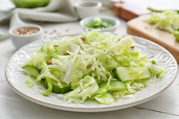 Plate with tasty cabbage salad on light wooden table, closeup