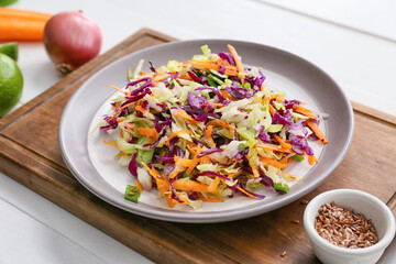 Board with tasty cabbage salad on light wooden table