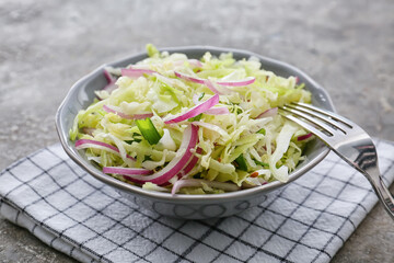 Bowl with tasty cabbage salad on grunge background
