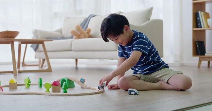 Happy little boy playing with toy train on floor,4K