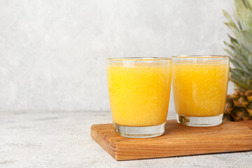 Glasses of tasty pineapple smoothie on light background
