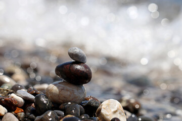 Tower of pebbles on blurred background of the sea waves. Summer vacation, balance and relax concept