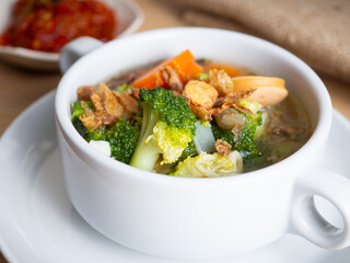 Vegetables soup that contain sausage, broccoli, carrots, etc on a white porcelain bowl