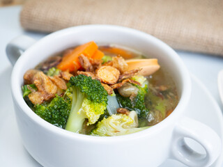 Vegetables soup that contain sausage, broccoli, carrots, etc on a white porcelain bowl