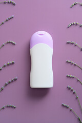 Natural shampoo bottle with lavender flowers on purple background. Flat lay, top view.