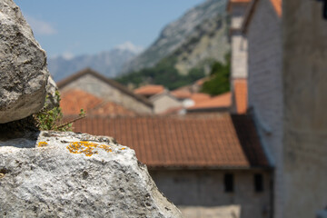 Big stone on the foreground. Red roofs of houses. Mountains, blue sky and old city on the background. 