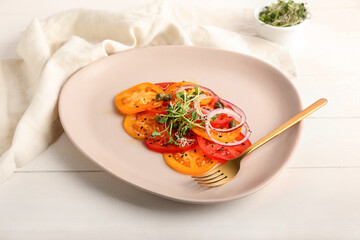 Plate with tasty tomato carpaccio on light wooden background