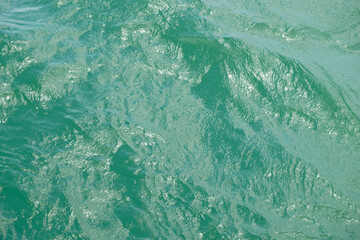 green waves on the sea reflecting sunshine - blurred image