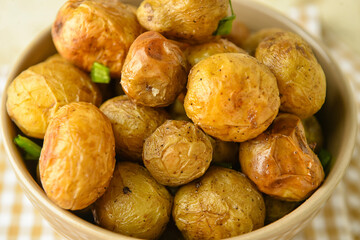 Bowl with tasty baked potato on table, closeup