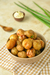 Bowl with tasty baked potato on light background