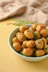 Bowl with tasty baked potato on color background