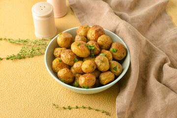 Bowl with tasty baked potato on color background