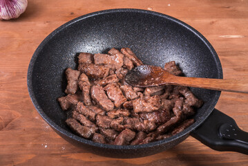 Cooking beef stroganoff - fried pieces of beef in a pan, the first step in making beef stroganoff