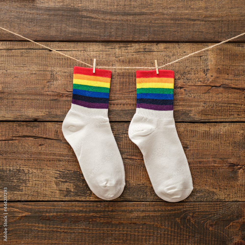 Wall mural pair of socks with rainbow edging on wooden background, idea for gift lgbt friends