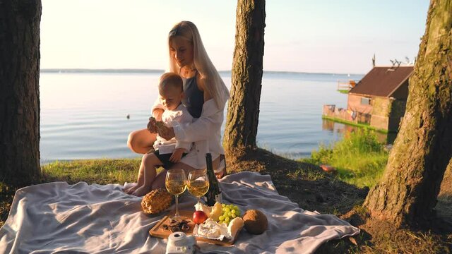 Beautiful elegant girl with her son having breakfast with a beautiful sea view