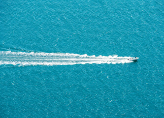 Naklejka premium Aerial view of blue sea and motor boat with wavy splash track on water surface