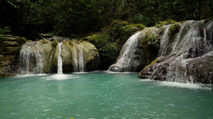 Fototapeta na wymiar Beautiful waterfall in the rainforest. Waterfall in the tropical mountain jungle. Philippines, Mindanao.